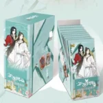 A pastel teal KAYOU Heaven Officials Blessing booster box sitting next to its matching upright card pack display showcasing Xie Lian and Hua Cheng artwork